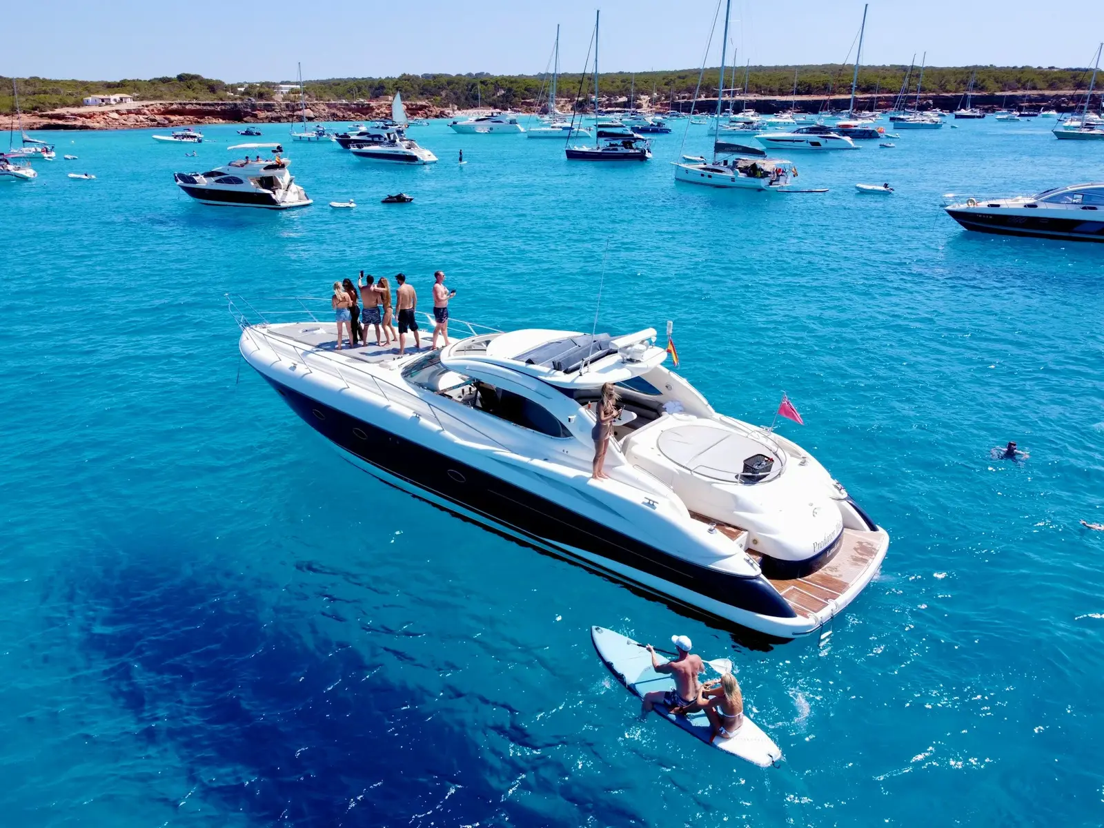 Lancha privada fondeada en una cala turquesa con bañistas en la Bahía de Palma, Mallorca