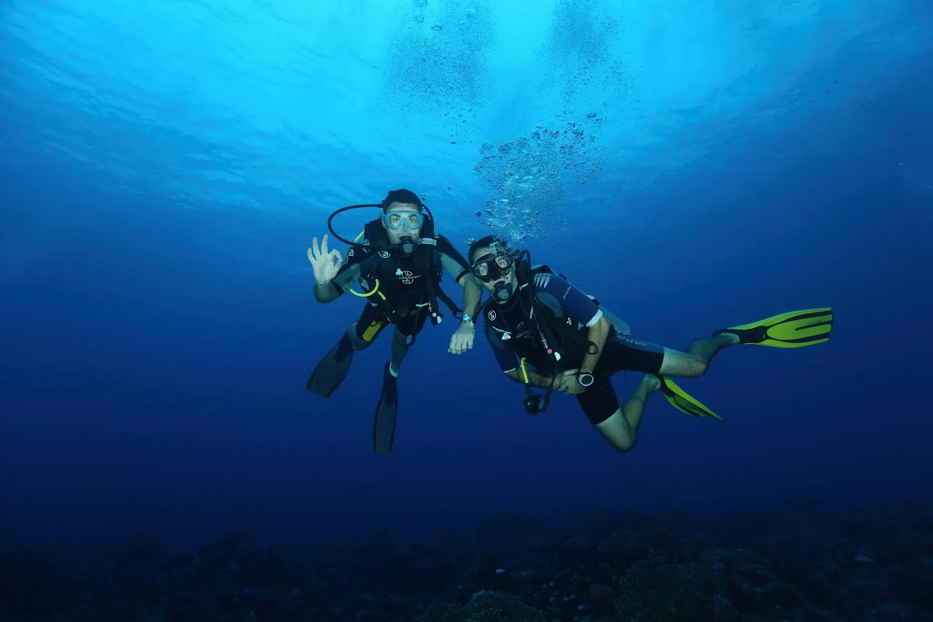 Buceador principiante con un instructor explorando un arrecife poco profundo en aguas azules y claras de Mallorca