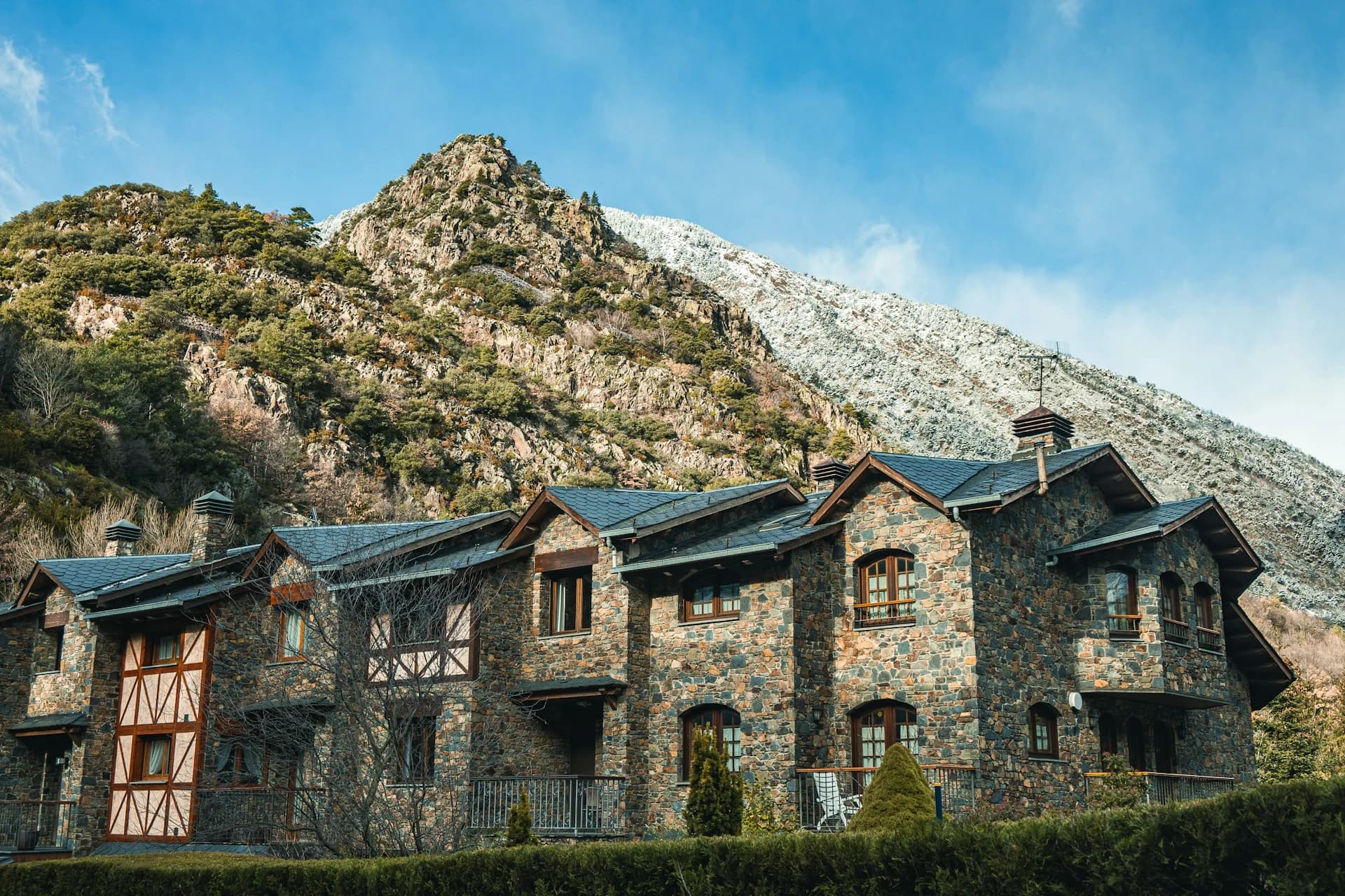A tour coach on a Pyrenees mountain pass with Andorra la Vella and snow peaks in the distance