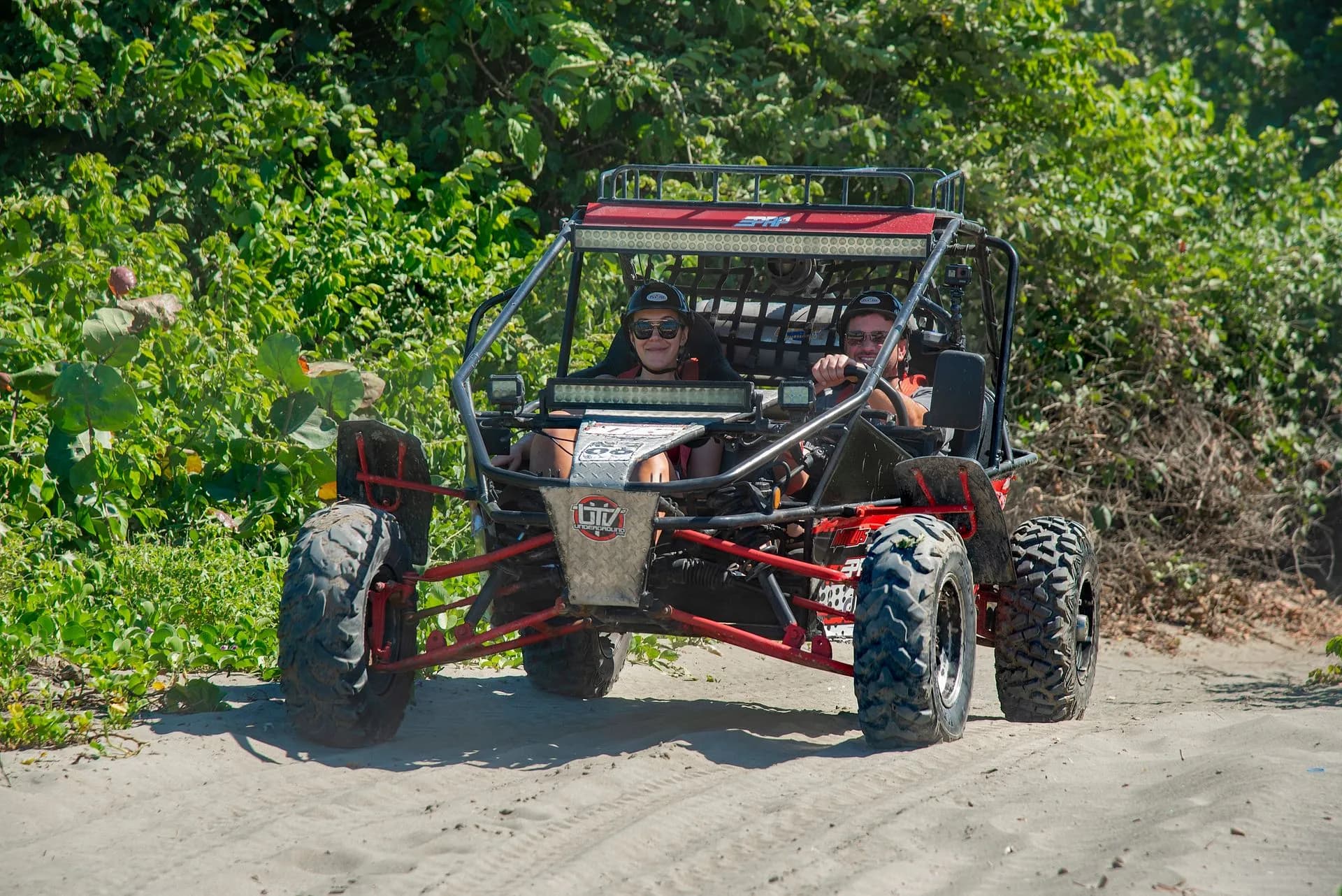 A line of quad bikes on a dusty off-road trail above a turquoise cove on the coast of Mallorca