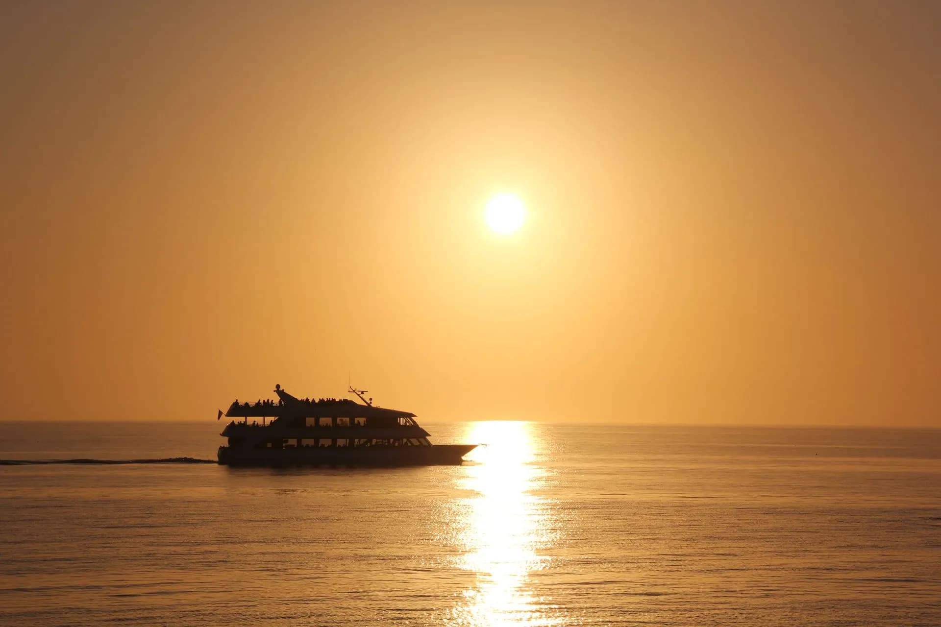 Catamaran sailing off Barcelona at golden hour with the city skyline glowing behind at sunset