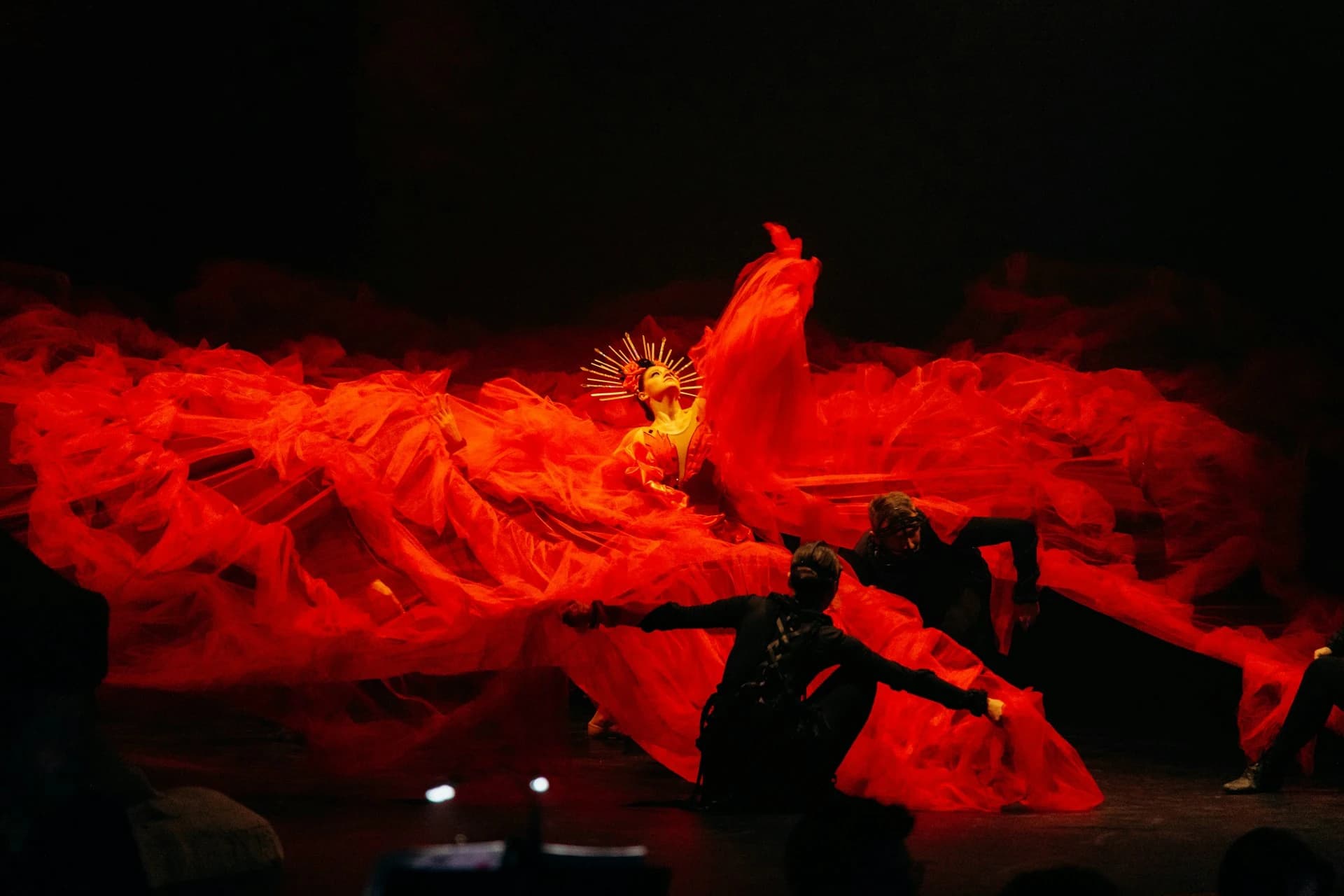 Bailaora de flamenco con vestido rojo actuando bajo cálidas luces de escenario en un tablao íntimo de Sevilla