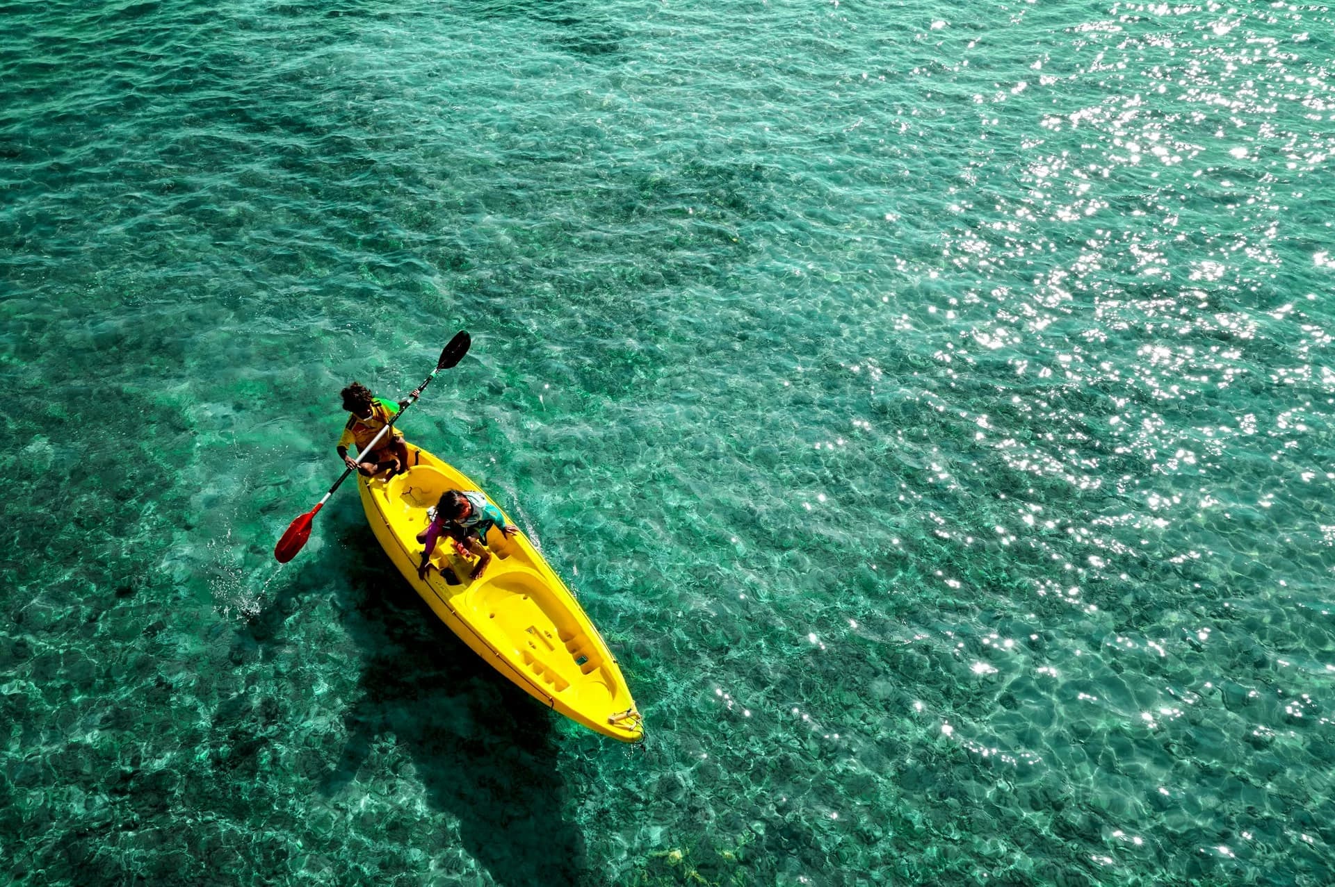 Kayakers paddling past dramatic cliffs and clear turquoise coves on the Costa Brava near Barcelona