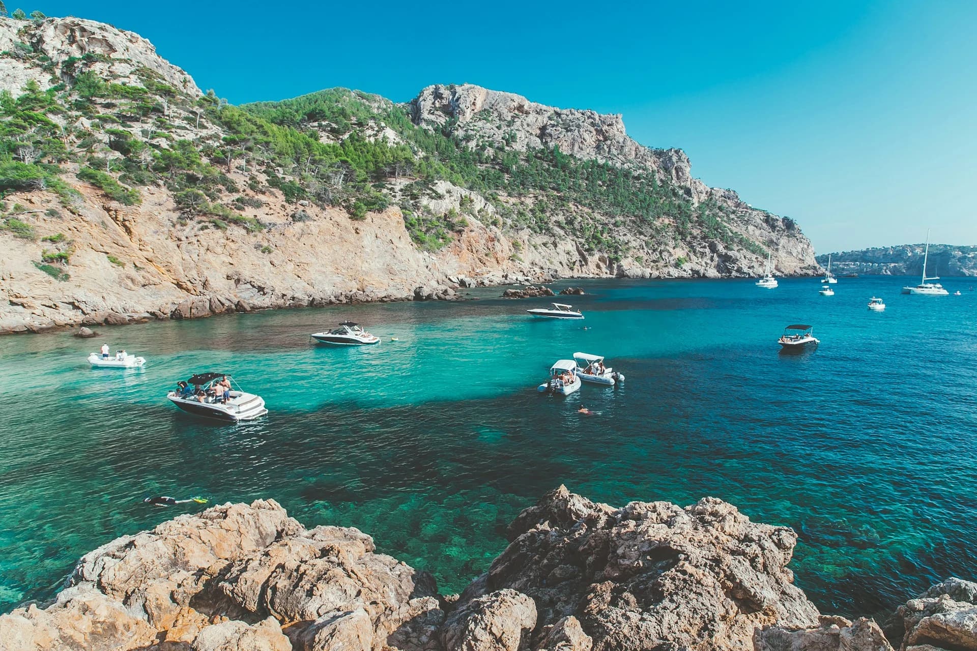 A packed Mallorca beach on a hot August day with a deep blue, warm sea and bright clear sky