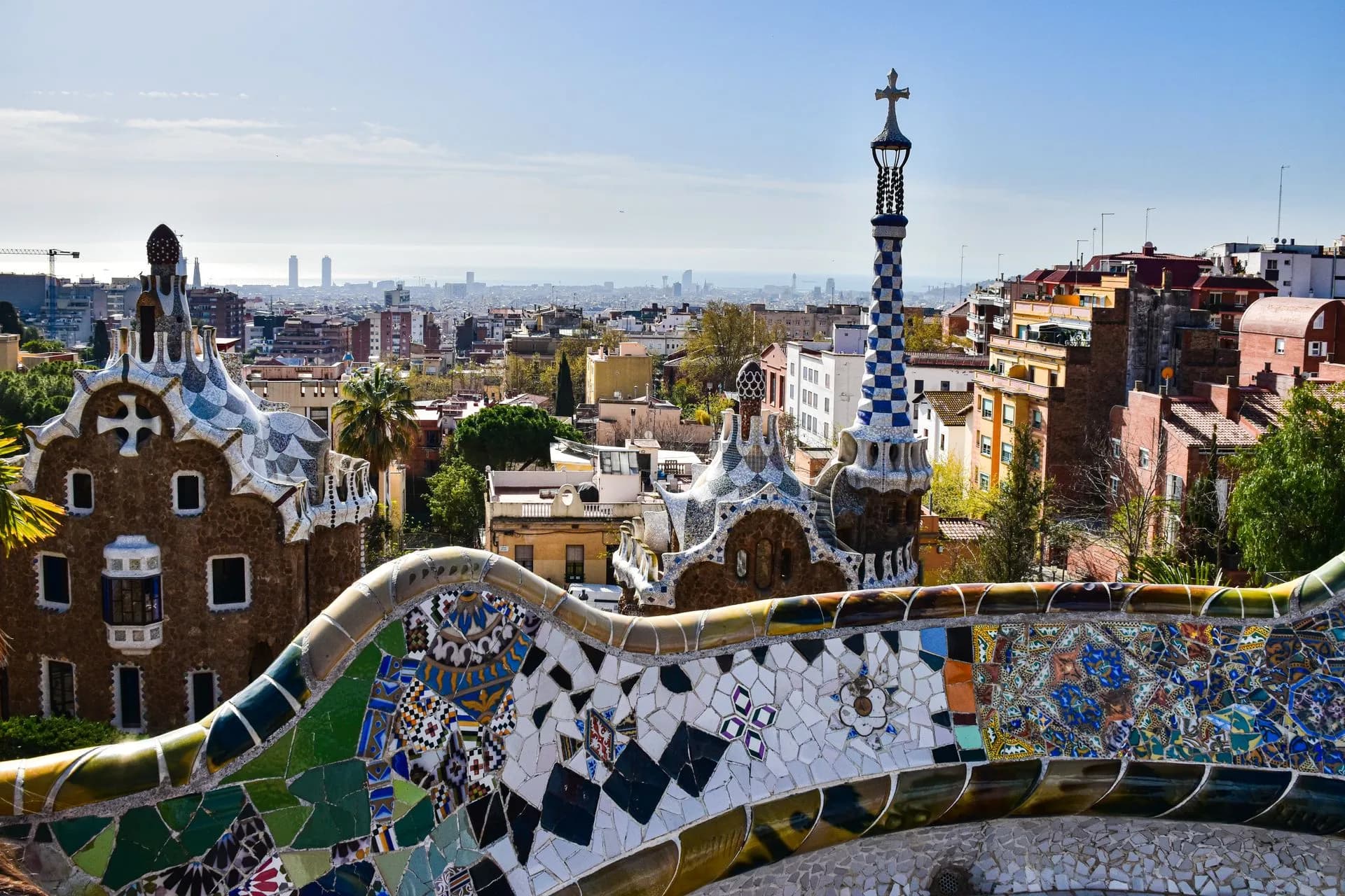 Guide leading a small group past Gaudí's mosaic terrace and columns at Park Güell in Barcelona