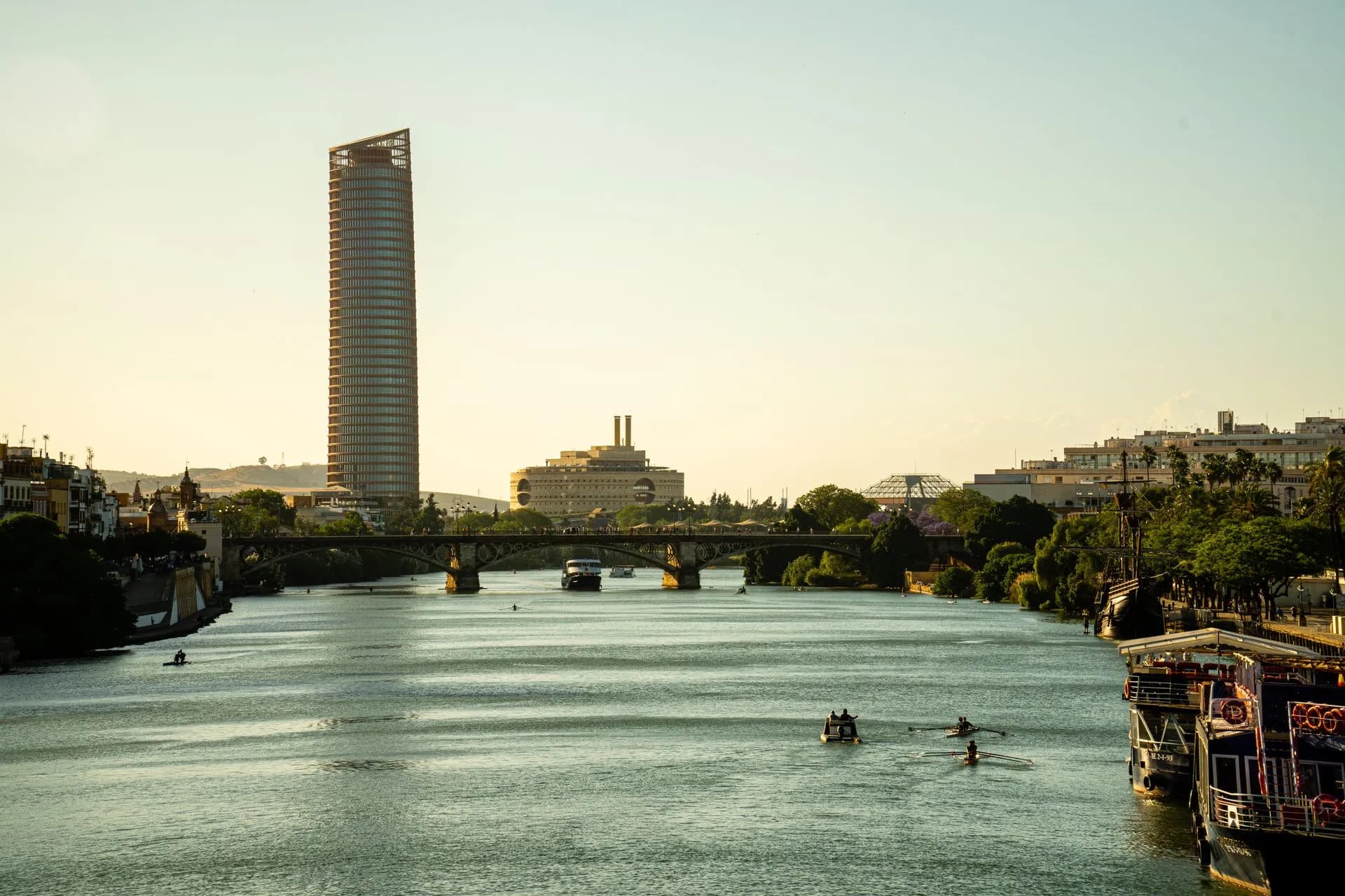 Barco turístico navegando por el río Guadalquivir junto a la Torre del Oro en Sevilla, España