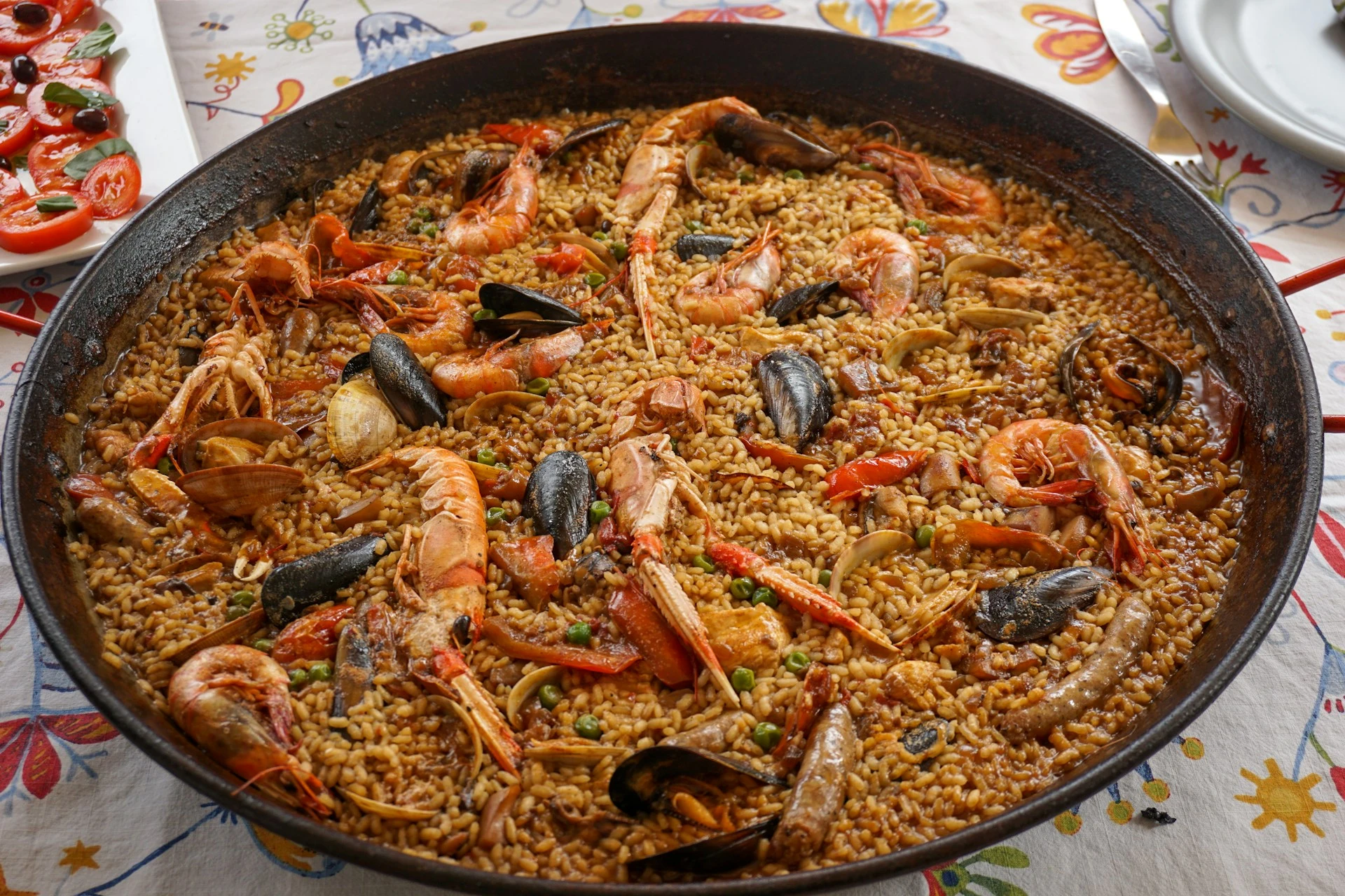 Paella pan full of saffron rice, chicken, and vegetables cooking at a Seville cooking class