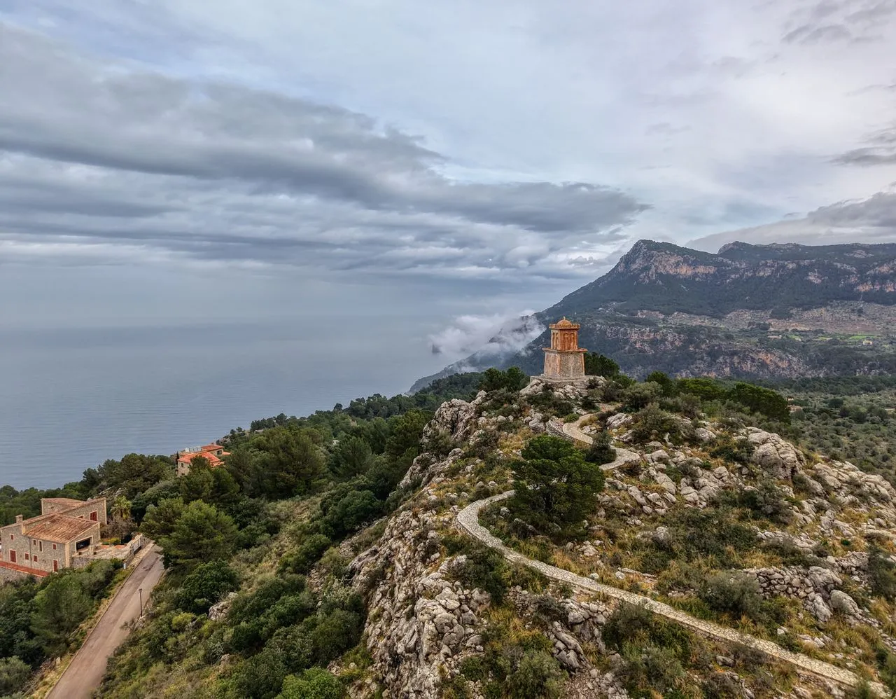 The rocky coastline and green slopes of the Serra de Tramuntana under a cloudy sky, Mallorca, Spain
